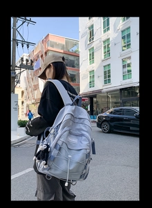 Close-up of light blue nylon backpack with multiple pockets and cute monkey plush pendant