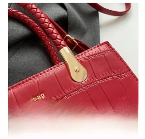 Detail view of red crocodile leather tote bag with woven handle and gold hardware accents