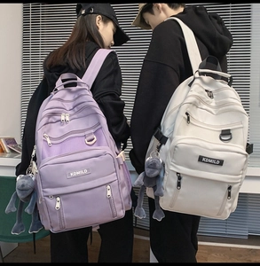 Couple wearing large capacity purple and beige backpacks with cute frog charms and front mesh detail