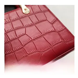 Close-up of red crocodile embossed leather tote bag with elegant gold metal hardware