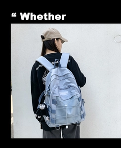Close-up of light blue nylon backpack featuring crossover ropes and a monkey keychain accessory