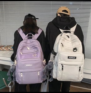 Close-up of large capacity nylon backpack details with mesh pockets and plush frog charms