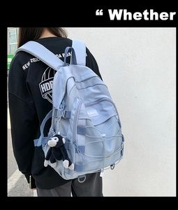 Blue waterproof nylon backpack with side buckle detail and black plush monkey charm