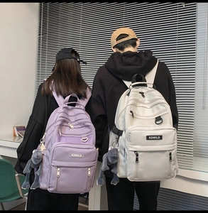 Detail view of purple and white school backpacks with multi-layer pockets and plush charm