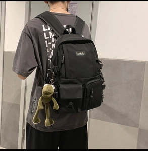Detail view of black high-density nylon backpack with green plush frog charm on side hook