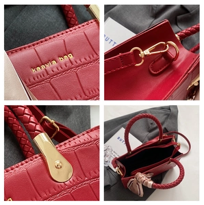 Detail of red crocodile embossed leather tote bag with woven handle and gold hardware