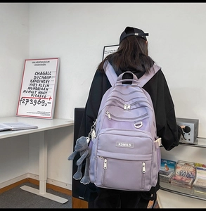 Detail view of purple multi-pocket backpack worn by a model in a minimalist studio