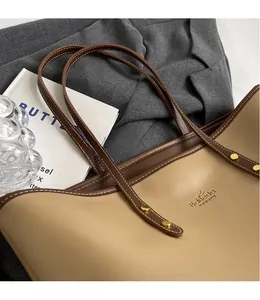 Close-up of soft khaki leather tote bag with brown trim and delicate golden rivets