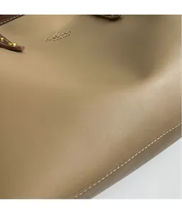 Detailed close-up of dark khaki leather tote with embossed logo and white stitching