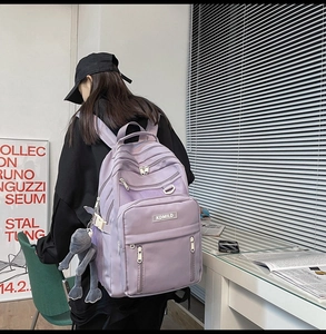 Detail of light purple nylon backpack with KDMILD logo and plush frog accessory