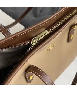 Close-up of golden zipper and smooth leather stitching on bicolor tote bag