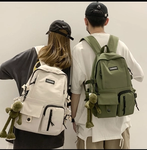 Detail of cargo-style nylon backpack with multiple functional pockets and a frog charm