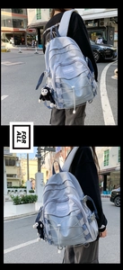 Detail of grey-blue backpack featuring crisscross elastic ropes and monkey plush charm