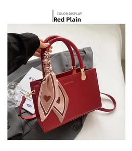 Detail of red leather tote bag with heart print silk scarf and golden hardware