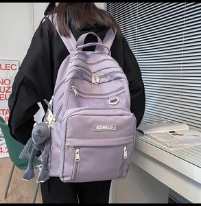 Detail view of purple multi-layer backpack with mesh pocket and cute frog charm