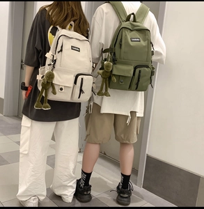 Close-up of minimalist nylon backpacks in beige and olive green with cute frog charms