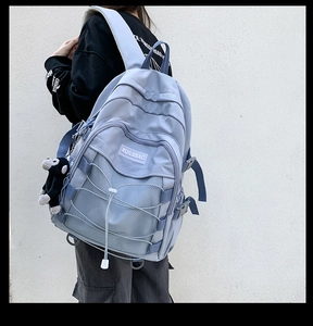 Detail view of light blue nylon backpack with mesh pocket and crisscross cord design