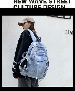 Detail of light blue nylon backpack featuring cross-elastic ropes and monkey keychain accessory