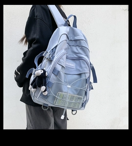 Detail of light blue waterproof nylon backpack with mesh layer and plush monkey pendant
