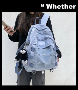 Detail view of light blue nylon backpack featuring mesh pockets and crisscross ropes