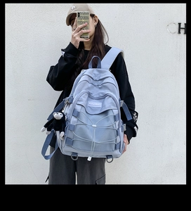 Close-up of light blue nylon backpack with crisscross cords and black monkey charm detail
