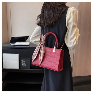 Detail of red crocodile texture tote bag with woven handles and silk scarf decoration
