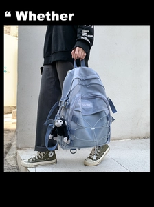Detail view of light blue canvas backpack with elastic rope decor and plush monkey charm