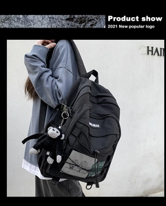 Detail of black multi-functional backpack with mesh side pocket and monkey plush charm