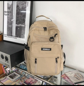Detailed close-up of a khaki nylon backpack with multi-layer zippers and mesh pockets