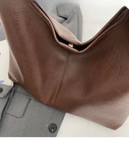 Detail of soft dark brown leather texture and metal buckle on the large hobo bucket bag