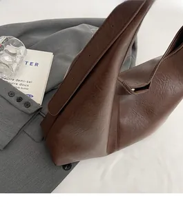Detailed view of dark brown leather bucket bag with white contrast stitching and wide strap