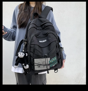 Detail of black nylon backpack with decorative bungee cords and cute monkey keychain