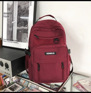 Detail view of burgundy large capacity backpack with multi-layer zipper bags and brand label