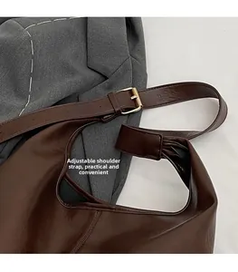 Detail view of the deep brown leather shoulder bag featuring an adjustable gold buckle strap