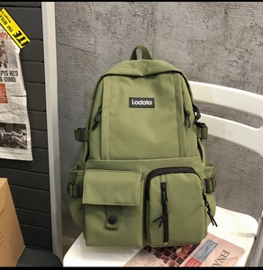 Detail of olive green canvas backpack with multiple pockets and side buckle straps
