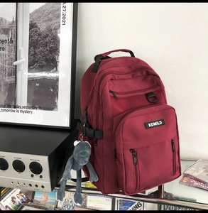 Maroon high-capacity backpack with multiple compartments and cute plush frog keychain