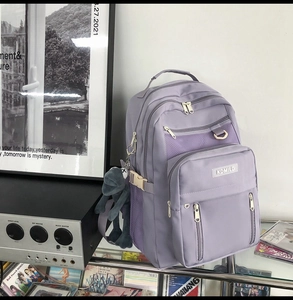 Close-up of light purple nylon backpack with multi-layer zippers and plush frog pendant