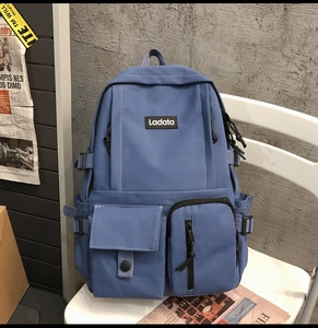 Detail of navy canvas backpack with Ladata logo patch and functional front pockets