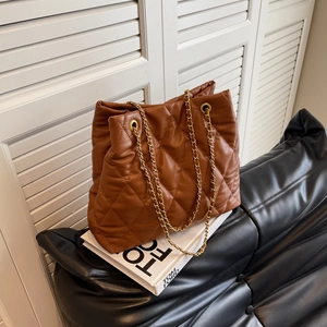 Chic brown quilted faux leather tote bag with gold chain strap on display books