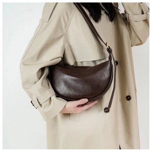 Detail of a dark brown crescent bag worn with a khaki trench coat for a stylish look
