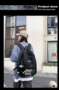 Detail of black nylon backpack featuring adjustable straps, side mesh and plush monkey charm