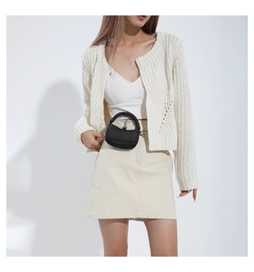 Chic beige knit cardigan paired with a white crop top and a mini black chain crossbody bag