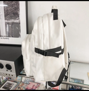 Detailed side view of white minimalist backpack with mesh side pockets and buckles