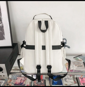 Close-up of beige student backpack with side mesh bottle pocket and cute doll keychain charm