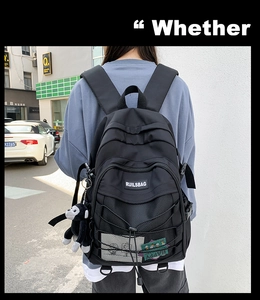 Close-up of black backpack with mesh pocket, elastic cords and a plush gorilla keychain