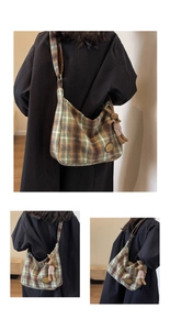 Detail of green plaid wool shoulder bag featuring a golden logo plate and cute bunny pendant
