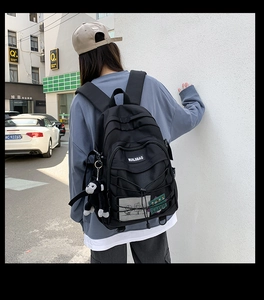Detail of black nylon school backpack featuring mesh pocket and elastic rope design