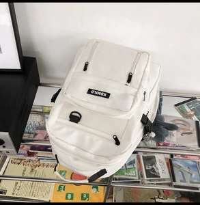 Close-up of white minimalist backpack with multi-layer zipper pockets and brand logo