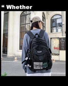 Street style shot of a black nylon backpack with mesh pocket and monkey charm detail