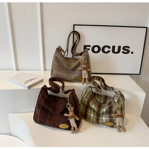 Detailed view of three wool plaid hobo bags in brown, burgundy, and green with cute charms